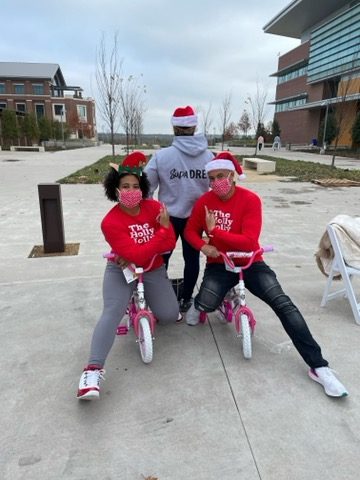 Volunteers having fun on the little bikes at Holly Jolly